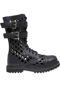 Stivale alla caviglia in pelle nera con design a lattice a intaglio, due cinghie con fibbie metalliche, punta rotonda e suola robusta e strutturata per una buona aderenza.