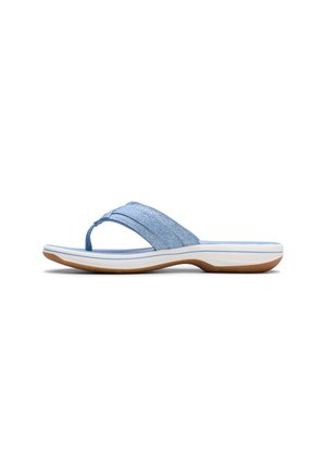 Hellblaue Denim-String-Sandale mit weißer gepolsterter Sohle und brauner Gummilaufsohle, von der Seite vor weißem Hintergrund gezeigt.