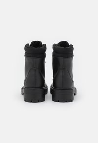Bottines noires en cuir, avec une doublure en fausse fourrure texturée et une semelle en caoutchouc durable dotée d'un motif de semelle robuste.