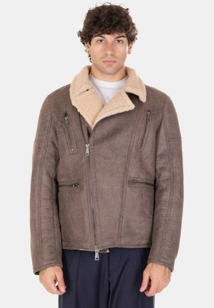 Giacca in camoscio marrone con colletto in shearling beige, zip frontale e due tasche laterali con zip, caratterizzata da una texture liscia e una vestibilità aderente.