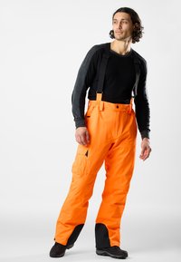 Oranje waterdichte broek met verstelbare zwarte bretels, voorzien van versterkte zwarte accenten bij de boorden en meerdere utiliteitszakken.