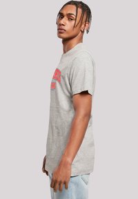 Gray cotton t-shirt with short sleeves, featuring red and blue printed text on the front. Classic crew neck, relaxed fit, and soft texture.