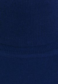 Tissu côtelé bleu marine avec une texture douce, doté d'une ceinture haute. Le motif se compose de lignes verticales créant un design régulier.