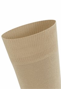 Calzino beige al ginocchio realizzato in materiale a coste con un risvolto ampio e aderente per comfort e vestibilità, caratterizzato da una texture uniforme e liscia.