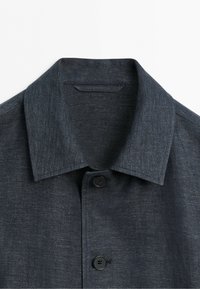 Dark gray long-sleeve shirt with a pointed collar and black buttons down the front shown against a white background.