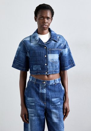 Denim crop-jakki ja korkea vyötäröiset housut, joissa on sininen sanomalehtipainatus, lyhyet hihat ja hopeiset napit.