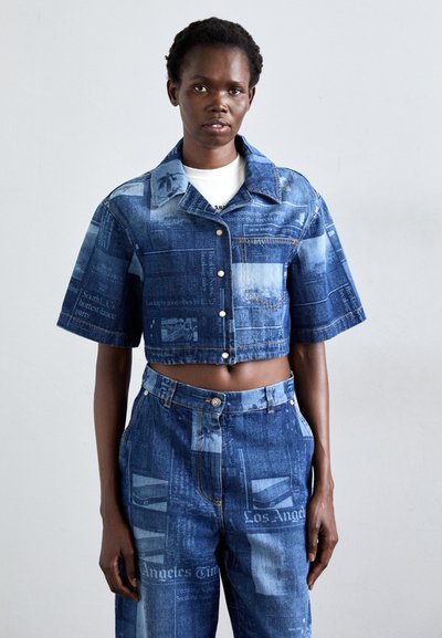 Denim cropjakke og højtaljede bukser med et blåt avisprint mønster, korte ærmer og sølvknapdetaljer.