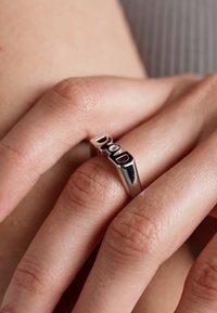 Hõbedane sõrmus, mille peal on kaaratud tähed "ISA" poleeritud pinnal, omades stiilset ja minimalistlikku kujundust. Rõnga pind on sile ja kumer.