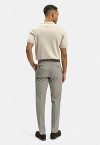 Ljust grå skräddarsydda byxor med en slät textur och två bakfickor, kombinerat med en ribbad, kortärmad beige skjorta.