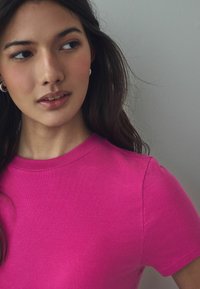 T-shirt a coste aderente in rosa brillante con scollatura rotonda e maniche corte, caratterizzato da un tessuto testurizzato per un effetto di maggiore profondità.