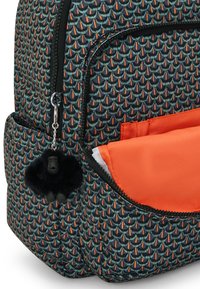 Zaino con un tessuto nero testurizzato che presenta un motivo di squame di pesce colorato. Fodera arancione all'interno della tasca frontale; include un charm per zip a forma di pom-pom nero.