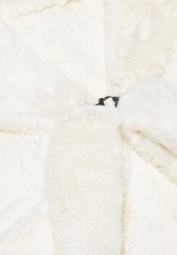 Vit fuskpäls tyg med en mjuk textur, med ett slätt svart spänne i mitten. Designen är plyschig med varierande texturer.