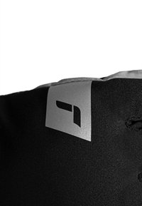 Schwarzes Stoffprodukt mit silbernem Logo-Patch. Verfügt über eine glatte Textur und eine abgerundete obere Kante. Schlichtes Design mit minimalen Details.