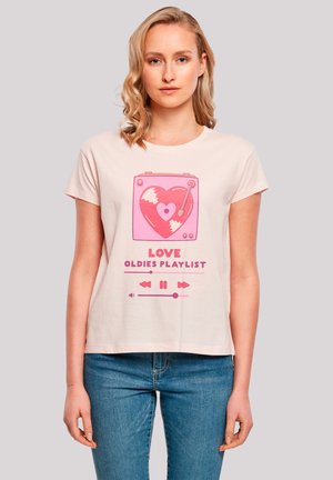 Light pink cotton T-shirt featuring a graphic design of a heart-shaped record player, text "LOVE OLDIES PLAYLIST," and play icons.
