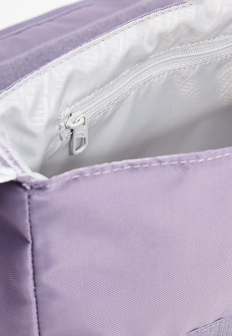Interior de una bolsa de tela morada con un revestimiento plateado suave y un bolsillo con cremallera que cuenta con un tirador de cremallera redondo. Tela exterior texturizada.