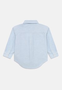 Camicia azzurra chiaro a maniche lunghe con bottoni e colletto, mostrata di schiena su uno sfondo bianco.