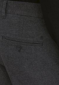Pantaloni in tessuto grigio con finitura strutturata, caratterizzati da una tasca posteriore con chiusura a bottone e un piccolo logo ricamato.