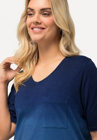 Mörkblå V-ringad t-shirt med en ombre-gradienteffekt. Korta ärmar och en liten framficka. Mjuk, strukturerad tyg.