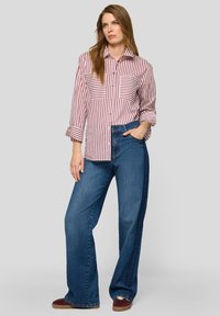 Red and white striped button-up shirt with two chest pockets, paired with loose blue jeans and burgundy shoes. Simple, casual design.