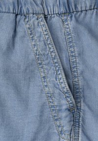 Tissu en denim bleu clair avec ceinture élastique et ouverture de poche doublement cousue avec surpiqûre jaune contrastante.