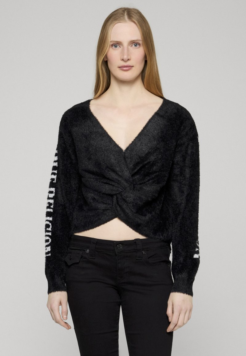 Czarny krótki sweter z głębokim dekoltem w serek, skręcanym przodem i długimi rękawami z białym napisem po jednej stronie. Miękka, puszysta faktura.