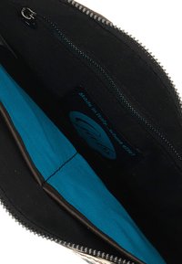 Interno di una borsa nera con cerniera, foderata con un vivace tessuto turchese, dotata di una piccola tasca con cerniera e una targhetta con la scritta "Made in Italy".