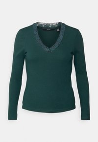 Mörkgrön ribbade långärmad topp med V-halsringning kantad med mörk blommig spets.