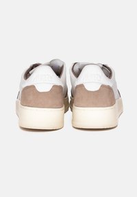 Zapatillas blancas con acentos de talón de ante marrón, parte superior de cuero suave y suela de goma texturada. Logotipo grabado en el talón. Diseño simple.