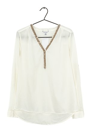 Blusa blanca de manga larga con escote en V adornada con detalles de cuentas doradas y plateadas, colgada en una percha negra.