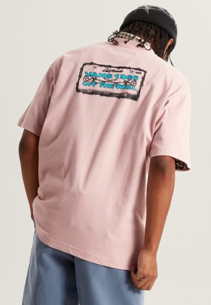 Camiseta rosa de manga corta con un diseño gráfico en la parte trasera que dice "VANS 1965 OFF THE WALL" en azul, borde negro y corte holgado.