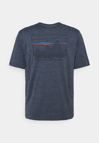 Mörkblå t-shirt med en bergskedje-grafik i grått, orange och blått, med texten "patagonia" och sloganen "SAVE OUR HOME PLANET".