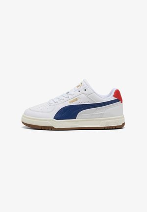 Sneaker bianca Puma con striscia blu laterale, linguetta rossa sul tallone, logo dorato, design con lacci e suola beige con battistrada marrone.