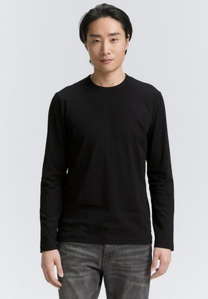 Black long-sleeve t-shirt made of a smooth, lightweight fabric. Features a crew neckline and fitted silhouette, paired with gray denim jeans.