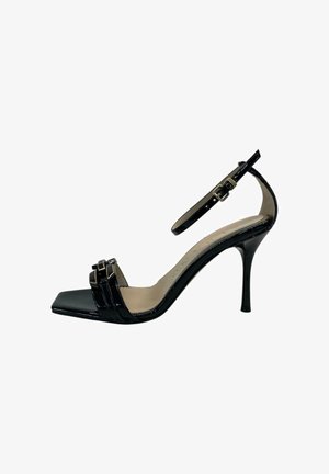 Sandalo alto con tacco in vernice nera, con cinturino alla caviglia, punta quadrata e due cinturini decorativi frontali con dettagli metallici.