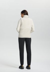 Lätt fleeceväst med hög krage, med en mjuk textur och en figurnära design, tillsammans med svarta tapered-byxor.