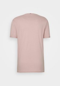 Light pink cotton t-shirt with short sleeves, round neck, and rolled sleeve cuffs. Features a small red, white, and blue tag at the back.