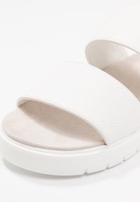 Bílé nazouvací sandály se dvěma širokými popruhy z texturované kůže, měkkou semišovou stélkou a silnou bílou platformou.