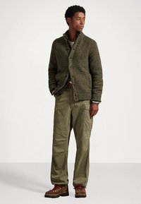 Olivengrønn strikket cardigan med teksturert stoff, knappelukking, kombinert med cargobukser og brune snøreboots. Casual passform med en avslappet silhuett.