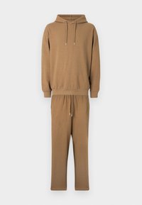 Καφέ φούτερ με κουκούλα και ταιριαστό παντελόνι φόρμας από μαλακό ύφασμα. Το μπλουζάκι έχει μπροστινή τσέπη, ενώ το παντελόνι διαθέτει ελαστική μέση με ρυθμιζόμενο κορδόνι.