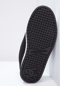 Musta kuminen tennarin pohja, jossa on kuvioitu pito. Varustettu valkoisella sivukorostuksella sekä kantapäässä ja välipohjassa olevalla brändäyksellä.