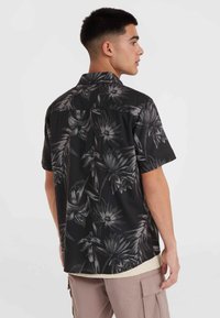 Zwart shirt met korte mouwen en een wit bloemenpatroon. Heeft een kraag en een relaxte pasvorm, gemaakt van lichtgewicht stof.