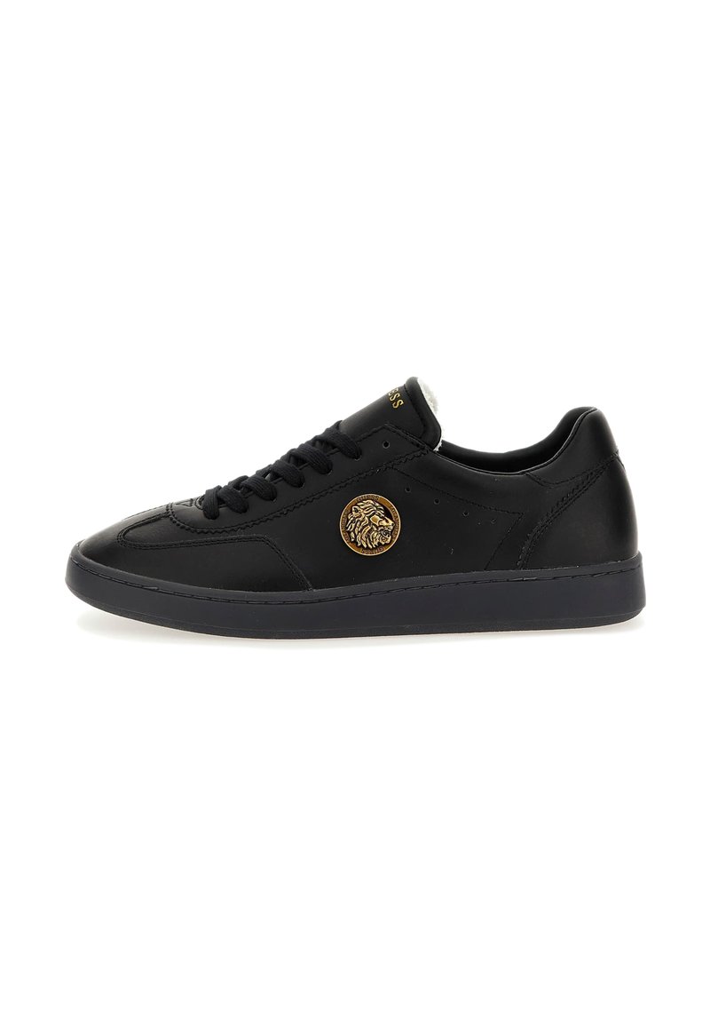 Sneaker in pelle nera con punta rotonda, emblema di leone dorato sul lato esterno, suola nera piatta e stringhe nere su sfondo bianco semplice.