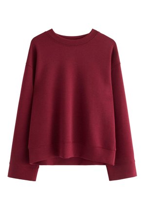 Sweatshirt oversize color bordeaux realizzato in morbido tessuto misto cotone. Presenta un colletto a girocollo, spalle scese e polsini a costine.