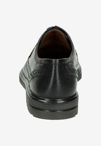 Zwarte leren schoen met een gladde afwerking, afgeronde hak en decoratieve brogue-details op de bovenkant. Binnenin is het bruin leer.