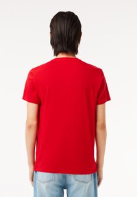 Rød T-shirt med korte ærmer og rund hals, lavet af blødt stof, med en glat tekstur og en tætsiddende pasform. Bagudsigten med ensartet design.