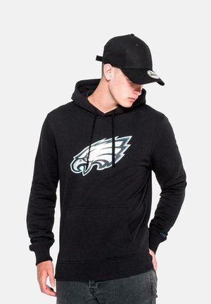 Schwarzer Hoodie mit einer vorderen Kängurutasche, versehen mit einem großen Philadelphia Eagles-Logo in Türkis und Weiß. Weiche, fleeceartige Textur.