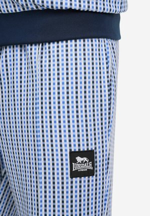 Modré športové nohavice s vzorom z mäkkej látky s rebrovaným pásom. Obsahujú malú čiernu nášivku s logom Lonsdale. Obdĺžnikový dizajn.