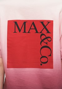 Ροζ βαμβακερό μπλουζάκι με βαθμιαία μετάβαση σε πιο σκούρο ροζ, με εμφανές κόκκινο τετράγωνο που περιέχει το κείμενο "MAX & Co." σε μαύρο.