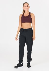 Sportig cropped topp i vinröd, tillsammans med svarta joggerbyxor med elastisk midja och mudd. Outfiten avslutas med svarta träningsskor.