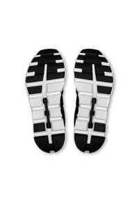 Semelles de chaussures de sport en noir et blanc avec un motif de semelle, présentant un mélange de caoutchouc noir texturé et de détails blancs pour l'adhérence.